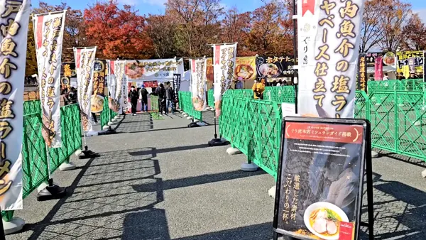のぼりが並ぶ屋台列。緑の柵に沿って並びます